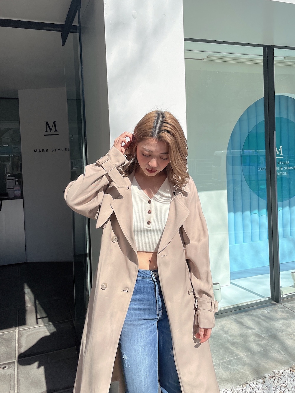 ホワイト系のニット/セーター、ベージュ系のトレンチコート、ブルー系のデニムパンツを着用したレディースの春コーディネートの4枚目の写真