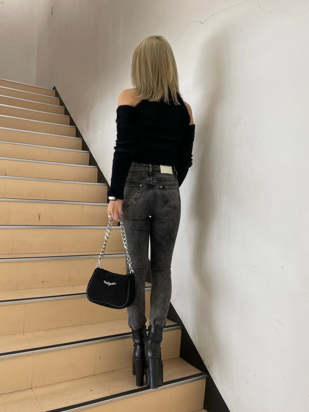 ブラック系のニット/セーター、ブラック系のデニムパンツ、ブラック系のブーツを着用したレディースの秋コーディネートの3枚目の写真