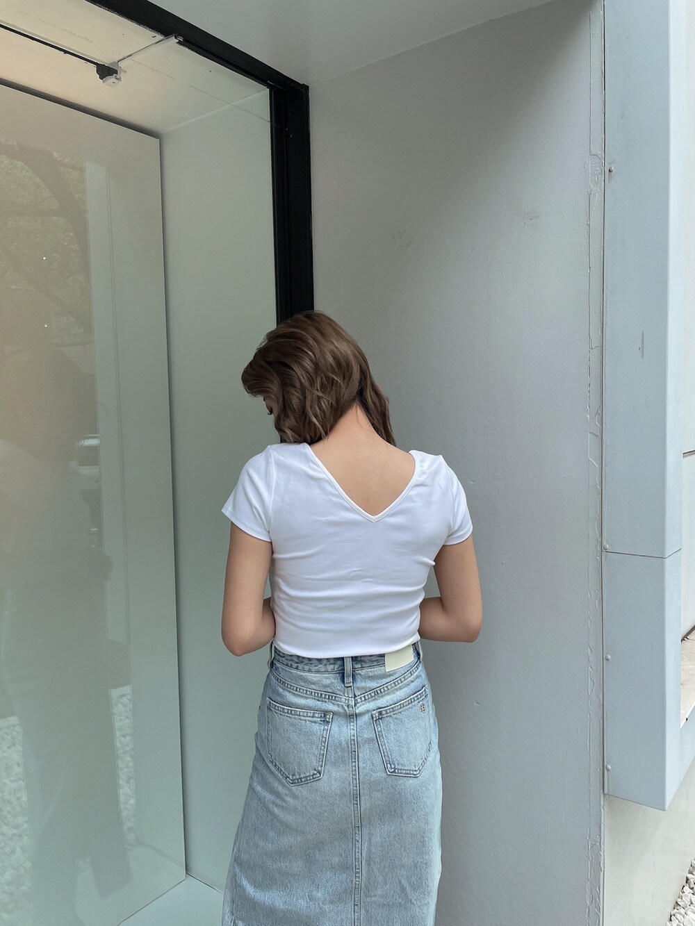 ブルー系のデニムスカート、ホワイト系のTシャツ/カットソー、ホワイト系のパンプスを着用したレディースの春コーディネートの5枚目の写真