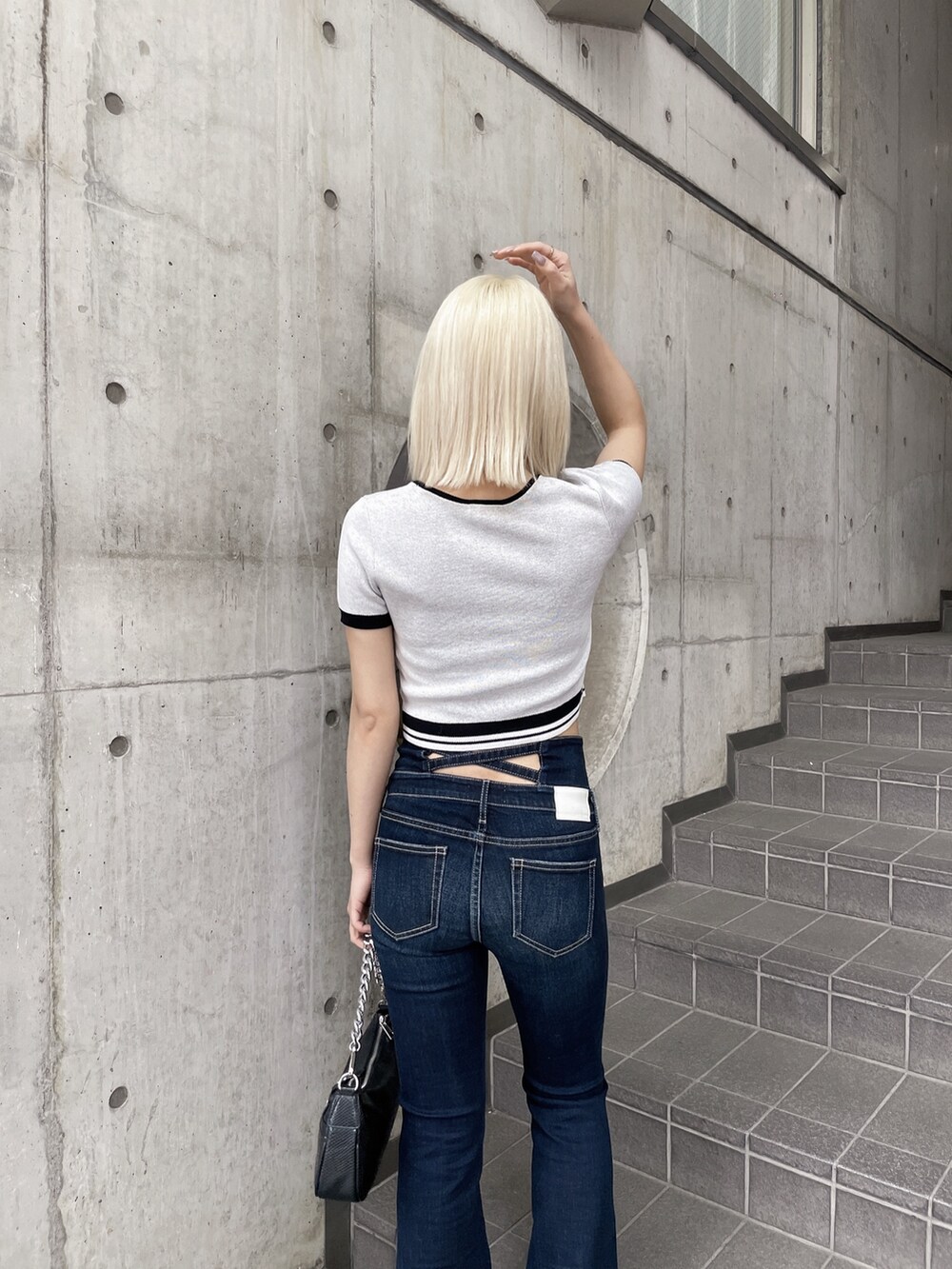 ホワイト系のニット/セーター、ブルー系のデニムパンツ、ブラック系のパンプスを着用したレディースの春コーディネートの5枚目の写真