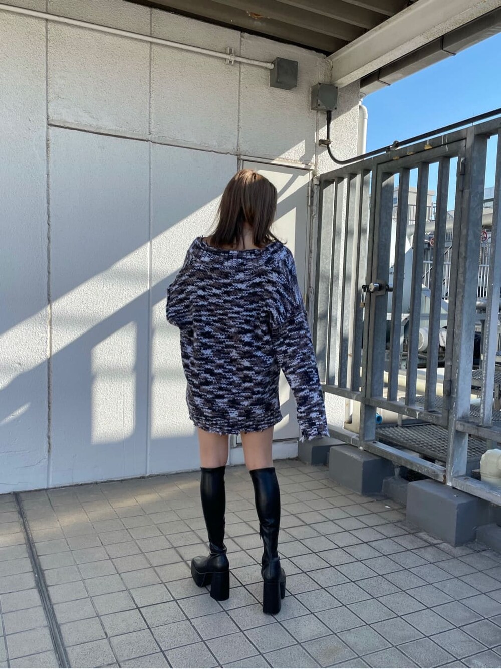 グレー系のニット/セーター、ブラック系のスカート、ブラック系のブーツを着用したレディースの秋コーディネートの4枚目の写真