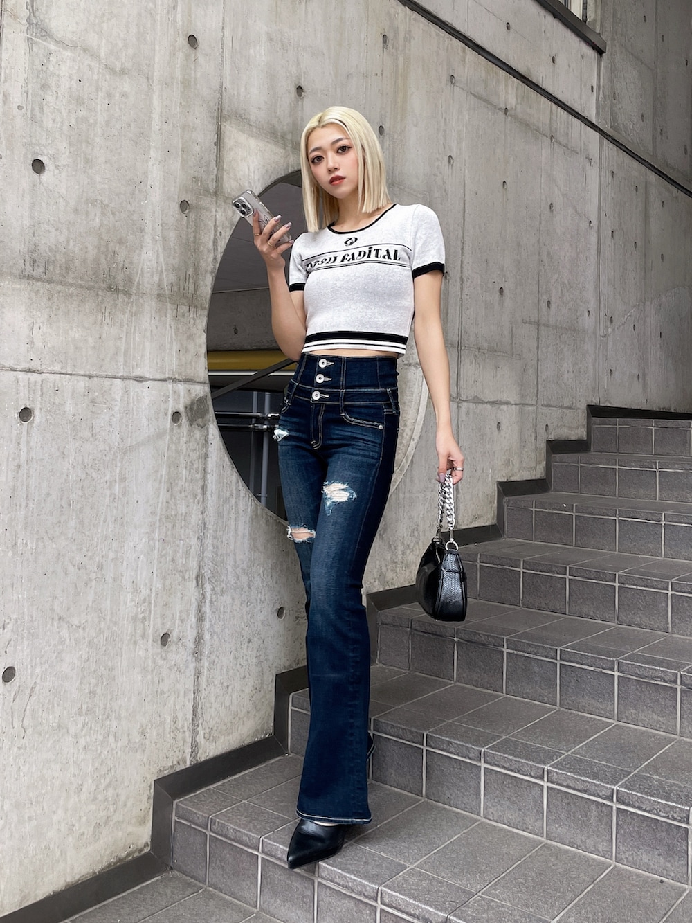 ホワイト系のニット/セーター、ブルー系のデニムパンツ、ブラック系のパンプスを着用したレディースの春コーディネートの2枚目の写真