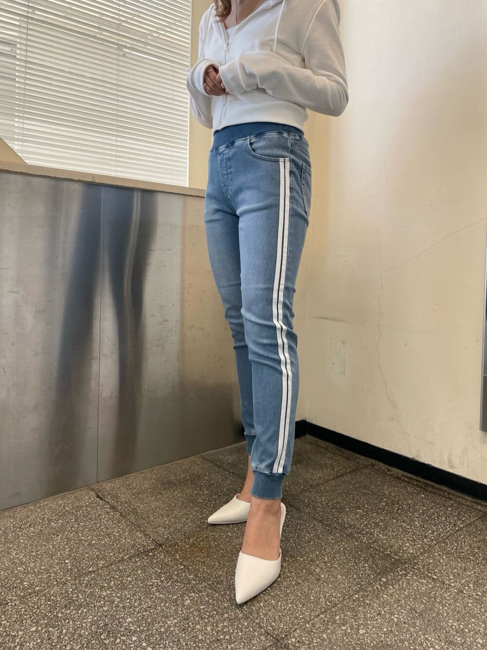 ホワイト系のパーカー、ホワイト系のパンプス、ブルー系のデニムパンツを着用したレディースの冬コーディネートの4枚目の写真