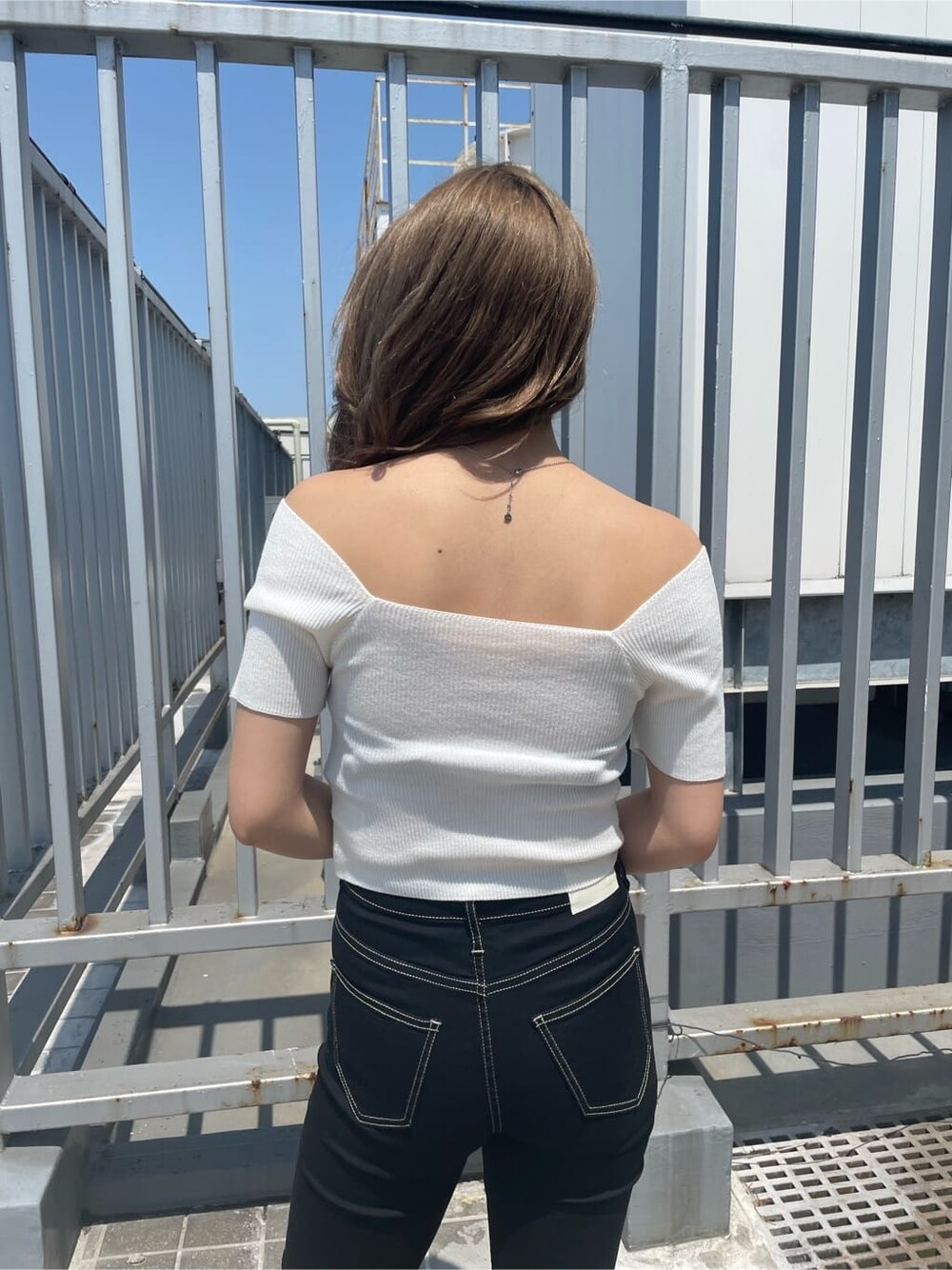 ブラック系のパンプス、ホワイト系のハンドバッグ、ホワイト系のニット/セーターを着用したレディースの春コーディネートの3枚目の写真