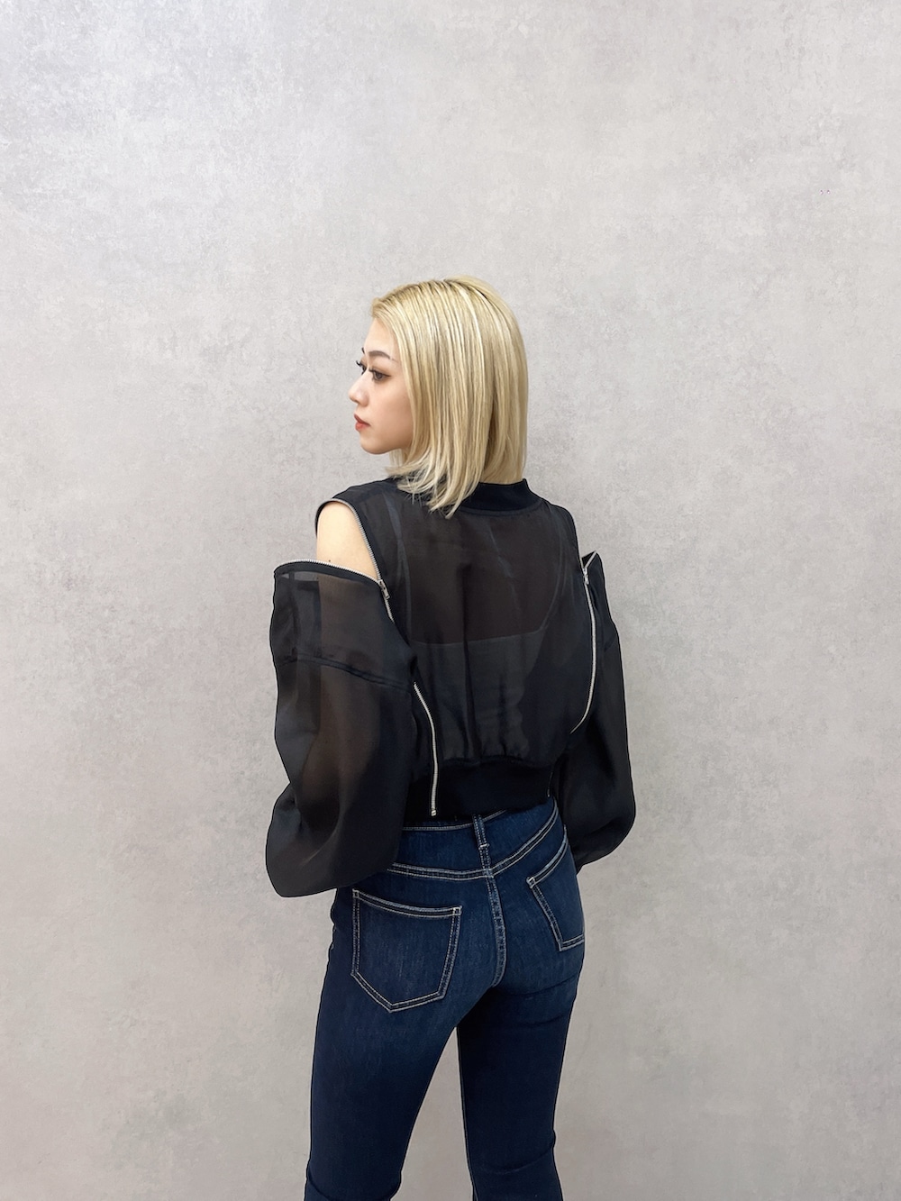 ブルー系のデニムパンツ、ホワイト系のキャミソール、ブラック系のブルゾンを着用したレディースの春コーディネートの5枚目の写真