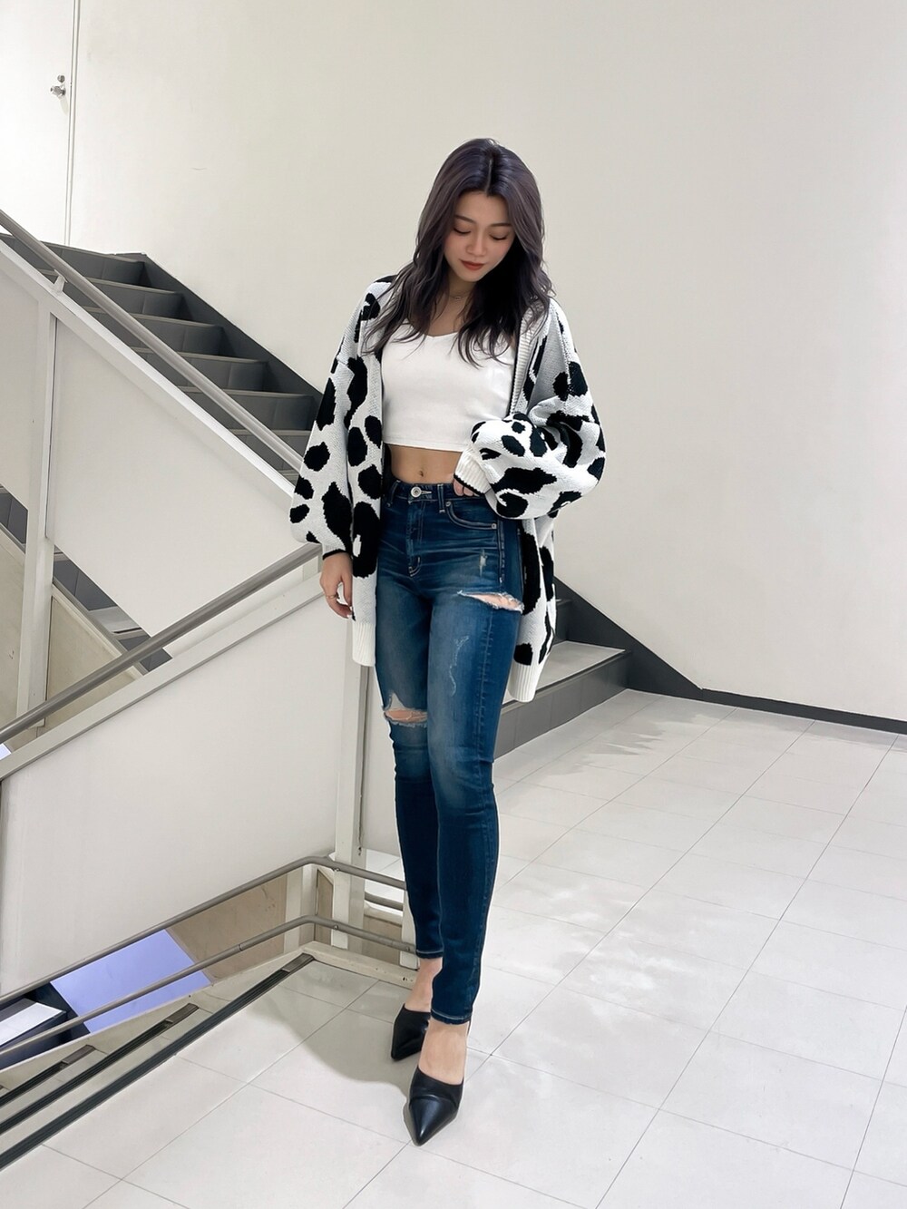 ブルー系のデニムパンツ、ブラック系のパンプス、ホワイト系のカーディガン/ボレロを着用したレディースの春コーディネートの2枚目の写真