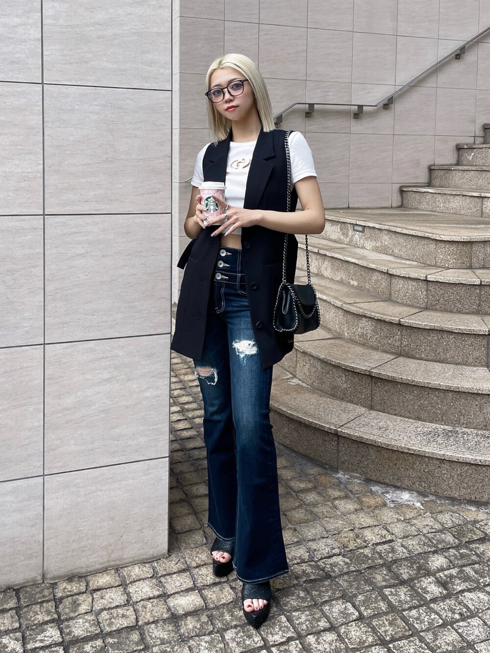 ブラック系のベスト、ホワイト系のTシャツ/カットソー、ブルー系のデニムパンツを着用したレディースの春コーディネートの2枚目の写真