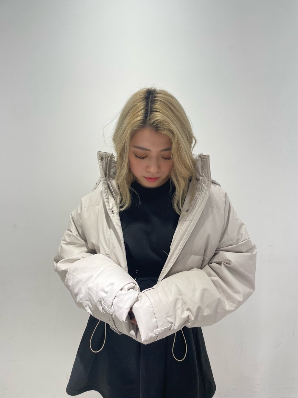 ブラック系のワンピース、ブラック系のブーツ、ホワイト系のダウンジャケット/コートを着用したレディースの冬コーディネートの7枚目の写真