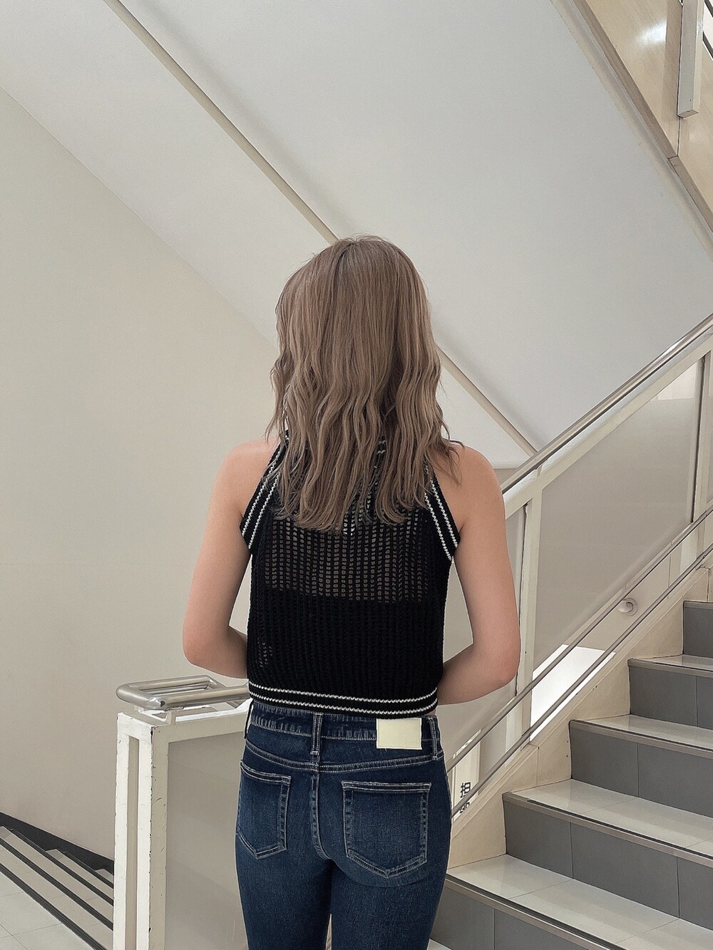 ブルー系のデニムパンツ、ブラック系のパンプス、ブラック系のニット/セーターを着用したレディースの夏コーディネートの6枚目の写真