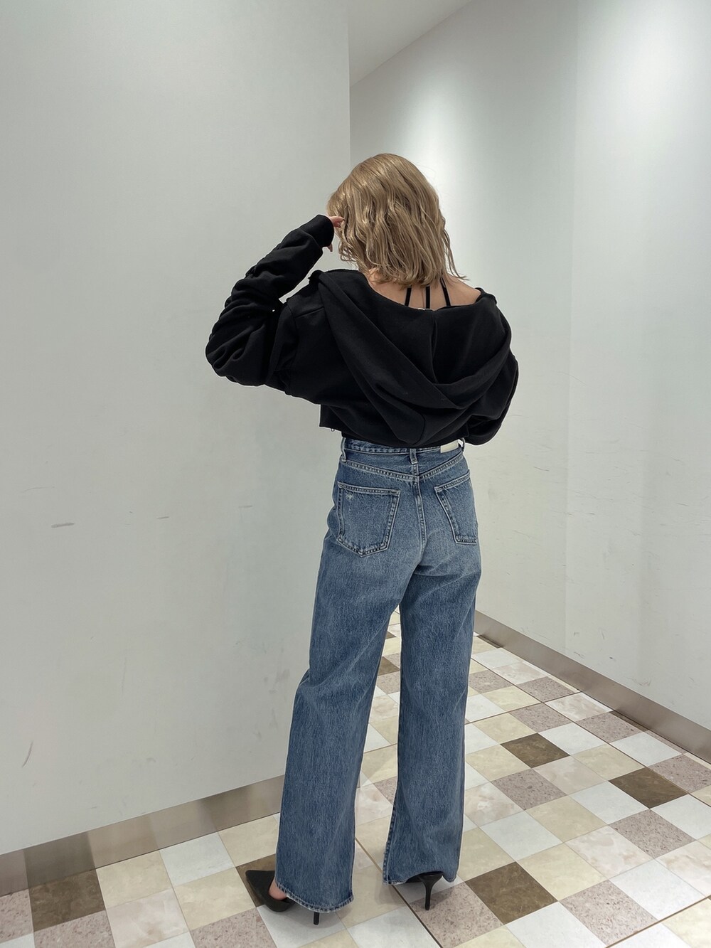 ブラック系のパーカー、ブルー系のデニムパンツ、ブラック系のパンプスを着用したレディースの冬コーディネートの2枚目の写真