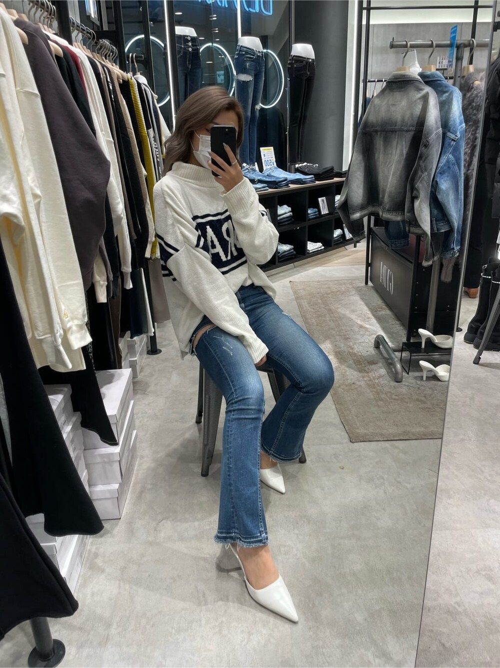 ホワイト系のニット/セーター、ホワイト系のパンプス、ブルー系のデニムパンツを着用したレディースの秋コーディネートの2枚目の写真