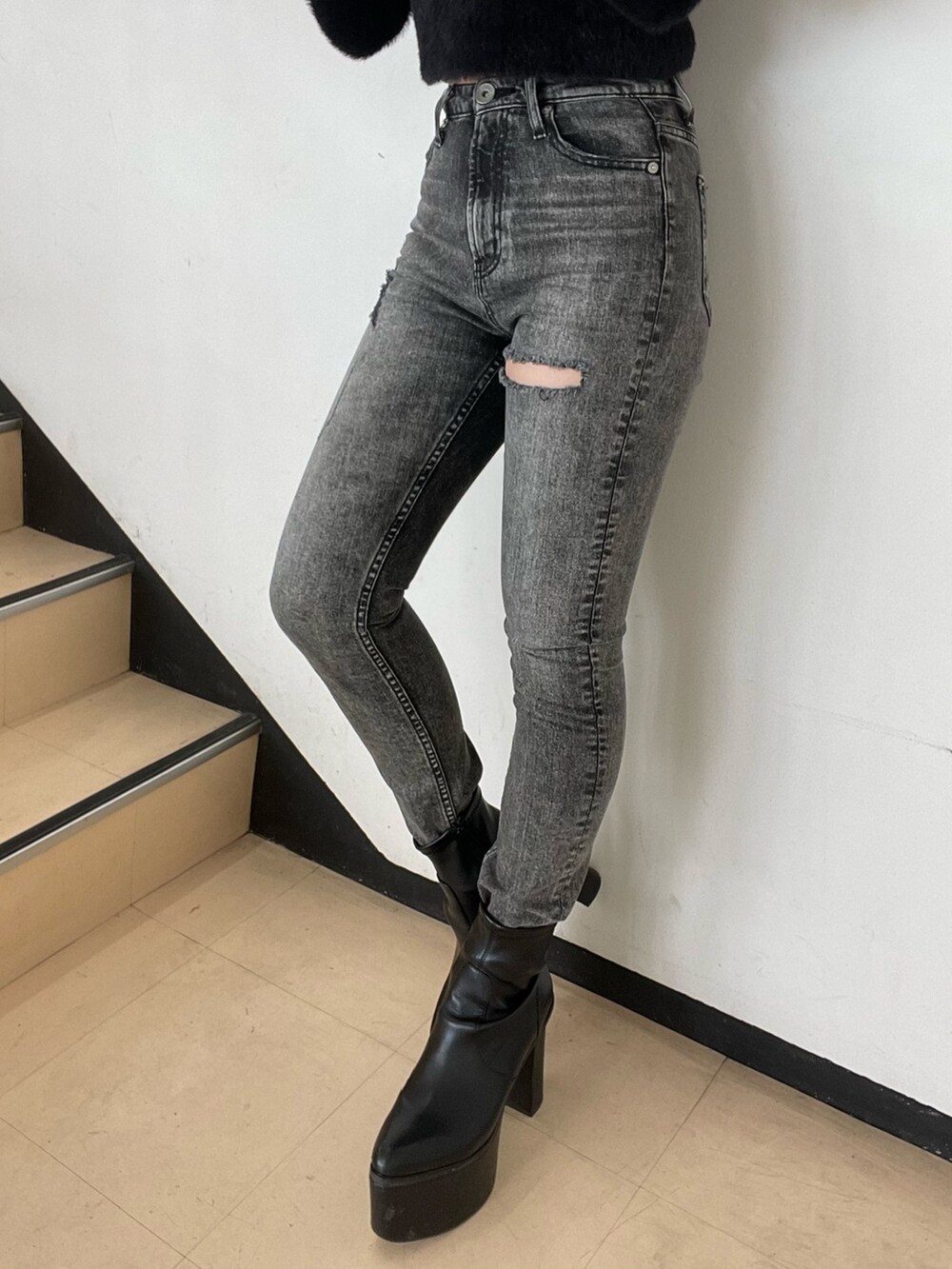 ブラック系のニット/セーター、ブラック系のデニムパンツ、ブラック系のブーツを着用したレディースの秋コーディネートの6枚目の写真