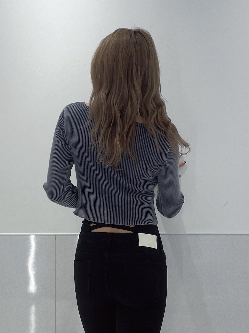 ブルー系のニット/セーター、ブラック系のデニムパンツ、ブラック系のブーツを着用したレディースの冬コーディネートの5枚目の写真