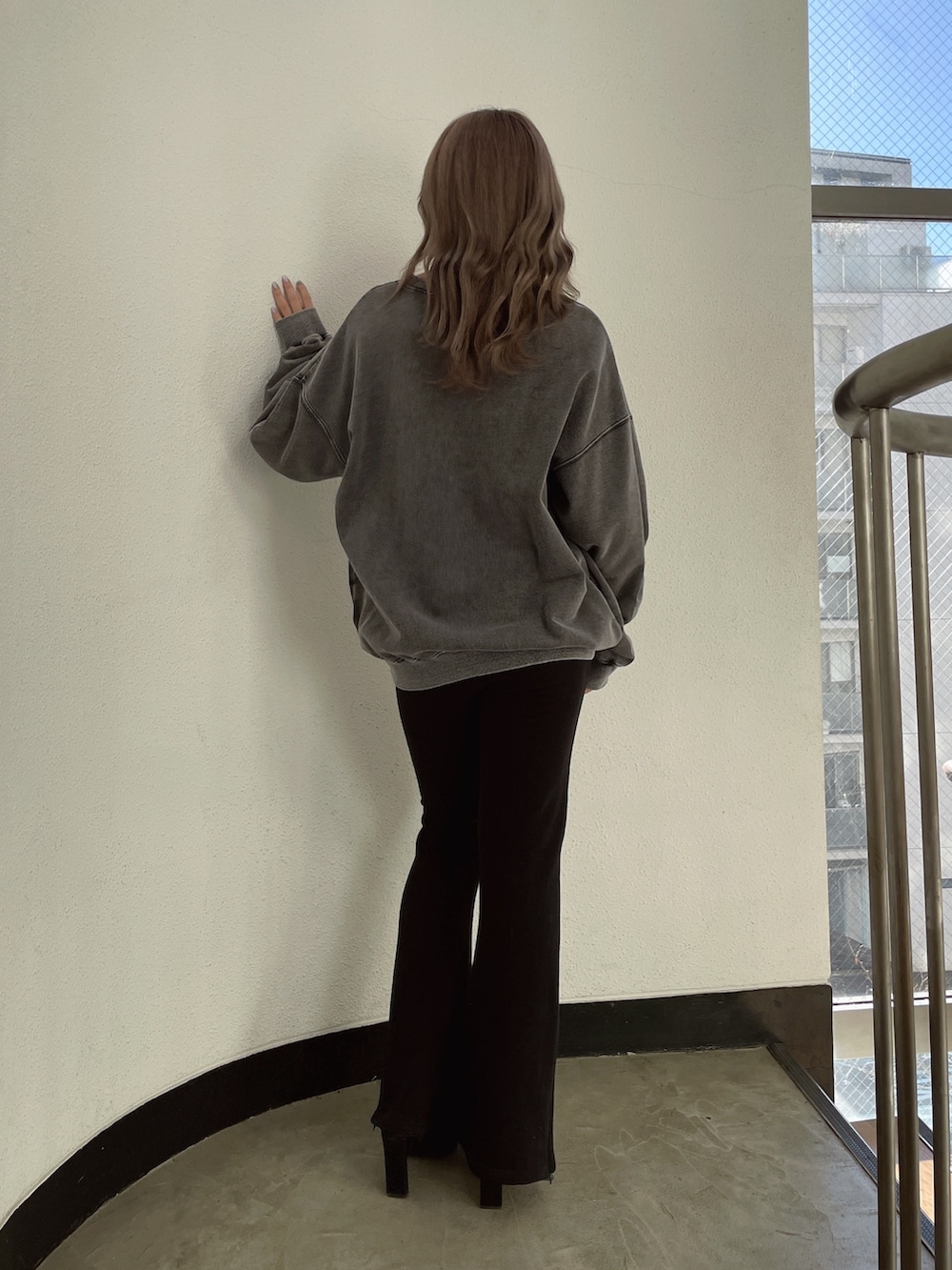 グレー系のスウェット、ブラック系のスウェットパンツ、ブラック系のパンプスを着用したレディースの冬コーディネートの3枚目の写真