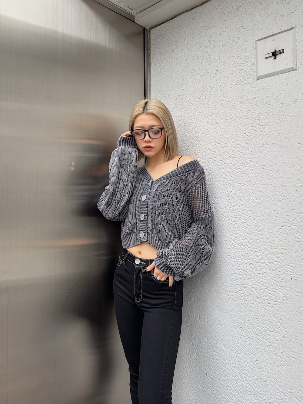 ブルー系のニット/セーター、ブラック系のデニムパンツ、ブラック系のサンダルを着用したレディースの春コーディネートの3枚目の写真