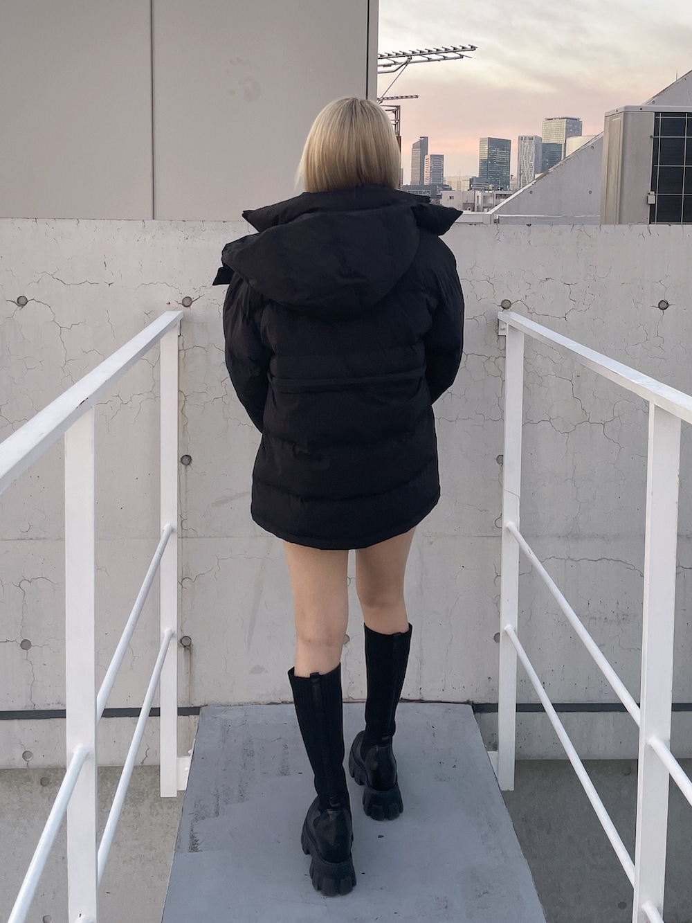 ブラック系のダウンジャケット/コート、ブラック系のデニムスカート、ホワイト系のニット/セーターを着用したレディースの冬コーディネートの3枚目の写真