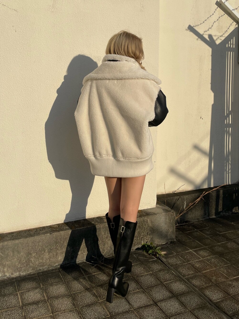 ホワイト系のブルゾン、ブラック系のブーツを着用したレディースの秋コーディネートの2枚目の写真