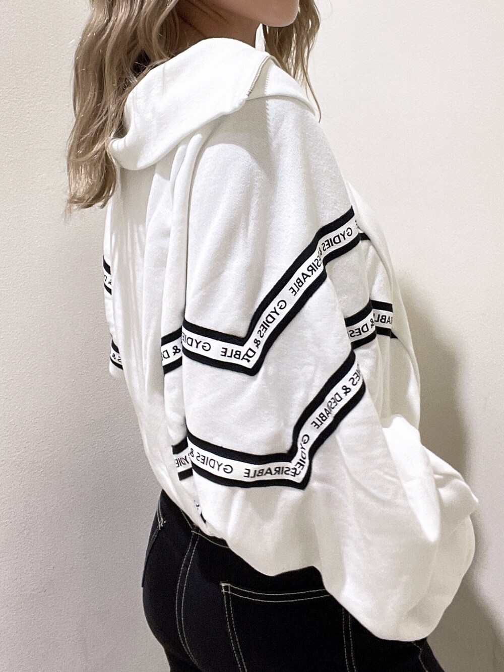 ホワイト系のスウェット、ブラック系のデニムパンツ、ブラック系のブーツを着用したレディースの秋コーディネートの5枚目の写真