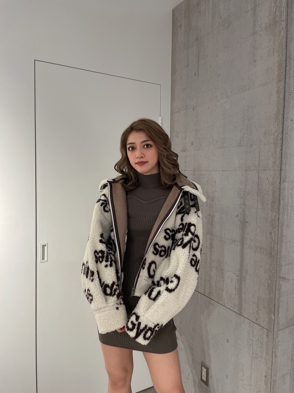 ホワイト系のブルゾン、グリーン系のワンピース、ブラック系のブーツを着用したレディースの冬コーディネートの4枚目の写真