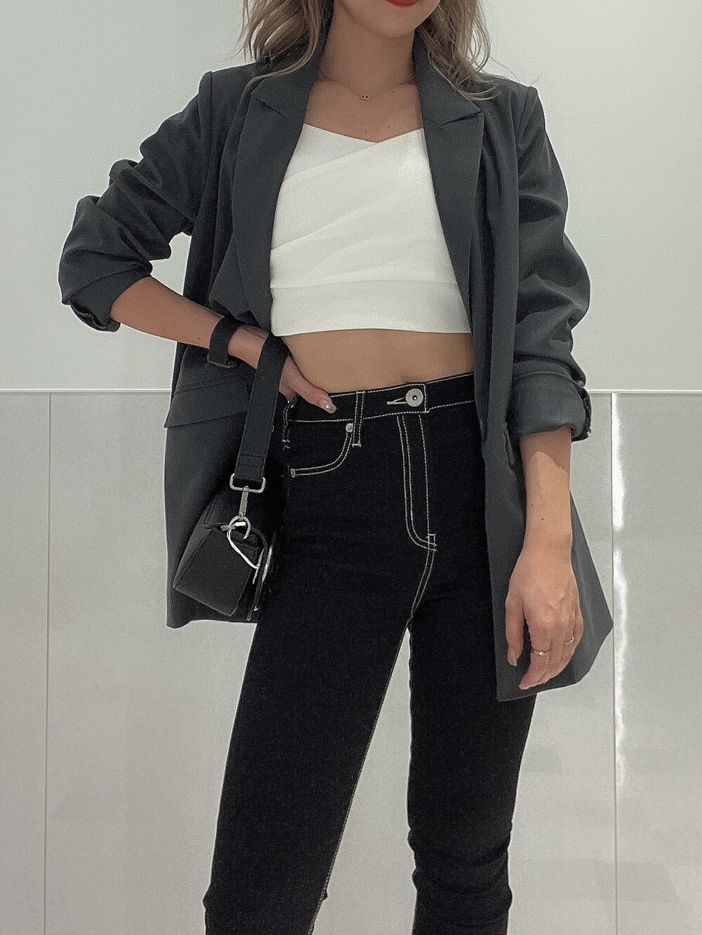 ブラック系のブーツ、ブラック系のデニムパンツ、ブラック系のハンドバッグを着用したレディースの秋コーディネートの5枚目の写真