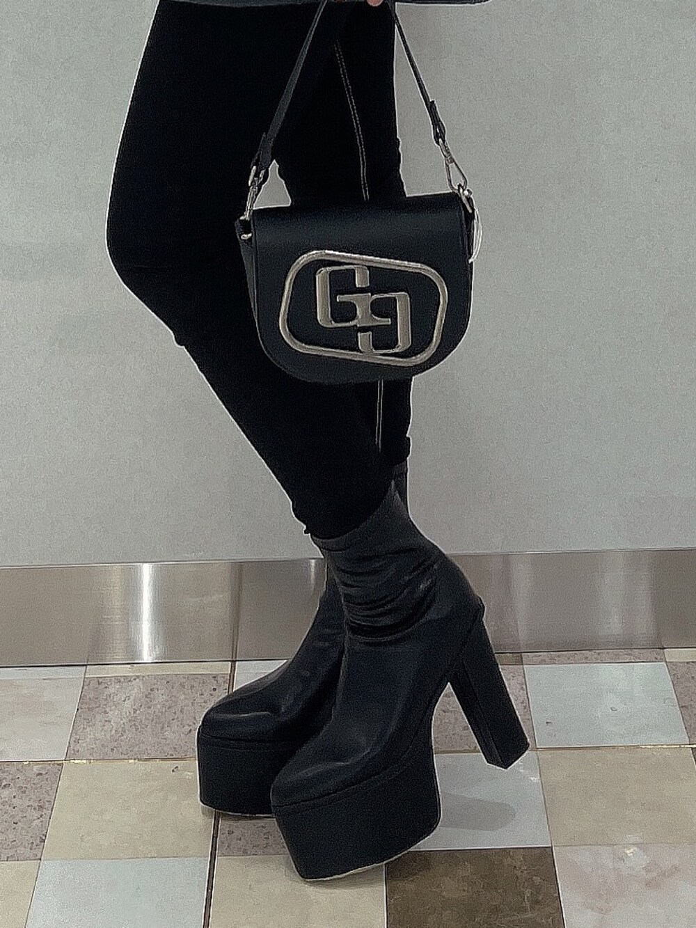 ブラック系のブーツ、ブラック系のデニムパンツ、ブラック系のハンドバッグを着用したレディースの秋コーディネートの8枚目の写真