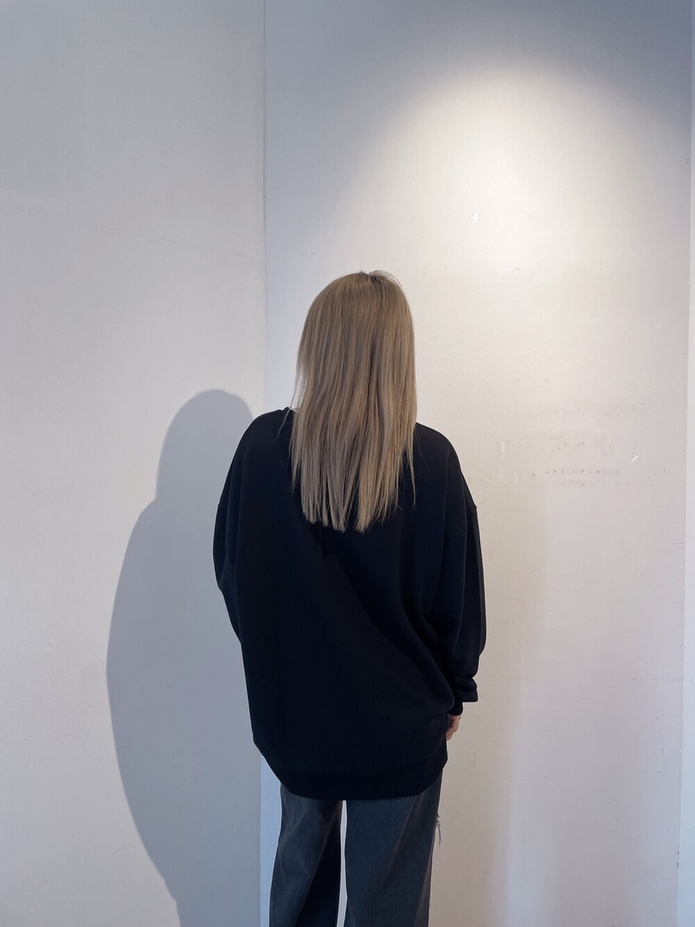 ブラック系のスウェット、ブラック系のデニムパンツ、ブラック系のブーツを着用したレディースの秋コーディネートの5枚目の写真