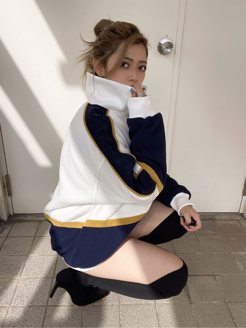 ホワイト系のブルゾン、ブラック系のブーツを着用したレディースの秋コーディネートの3枚目の写真