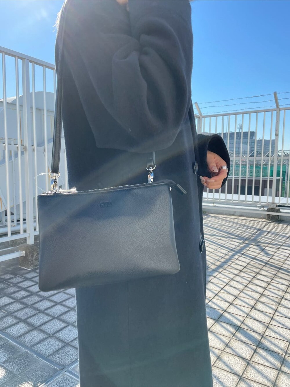 ブラック系のブーツ、ブラック系のニット/セーター、ブラック系のチェスターコートを着用したレディースの秋コーディネートの4枚目の写真