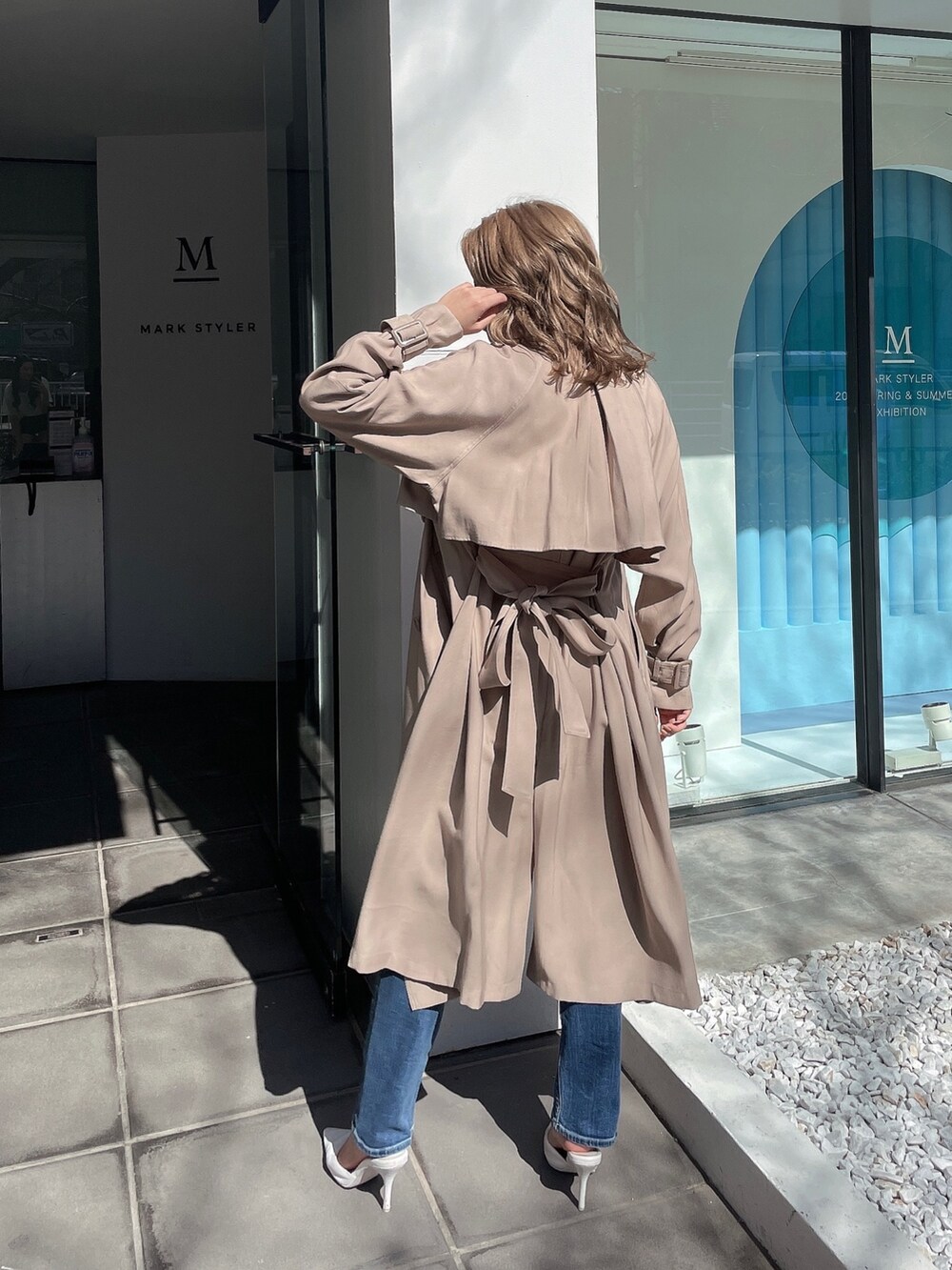 ホワイト系のニット/セーター、ベージュ系のトレンチコート、ブルー系のデニムパンツを着用したレディースの春コーディネートの3枚目の写真