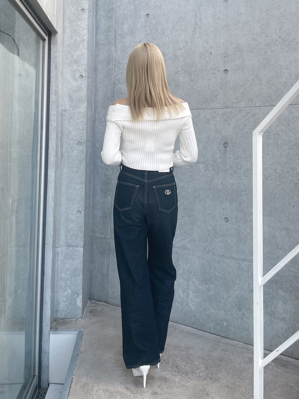 ホワイト系のニット/セーター、ブルー系のデニムパンツ、ホワイト系のパンプスを着用したレディースの冬コーディネートの3枚目の写真