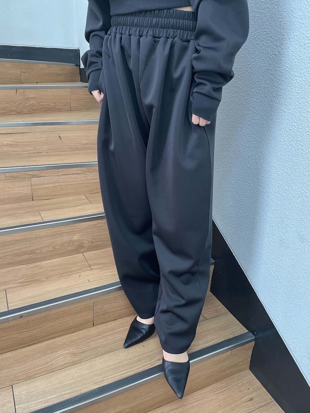 ブラック系のTシャツ/カットソー、ブラック系のスウェットパンツ、ブラック系のパンプスを着用したレディースの冬コーディネートの7枚目の写真