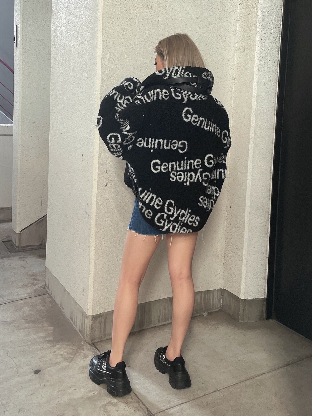 ブラック系のブルゾン、ブルー系のデニムスカート、ブラック系のスニーカーを着用したレディースの秋コーディネートの2枚目の写真