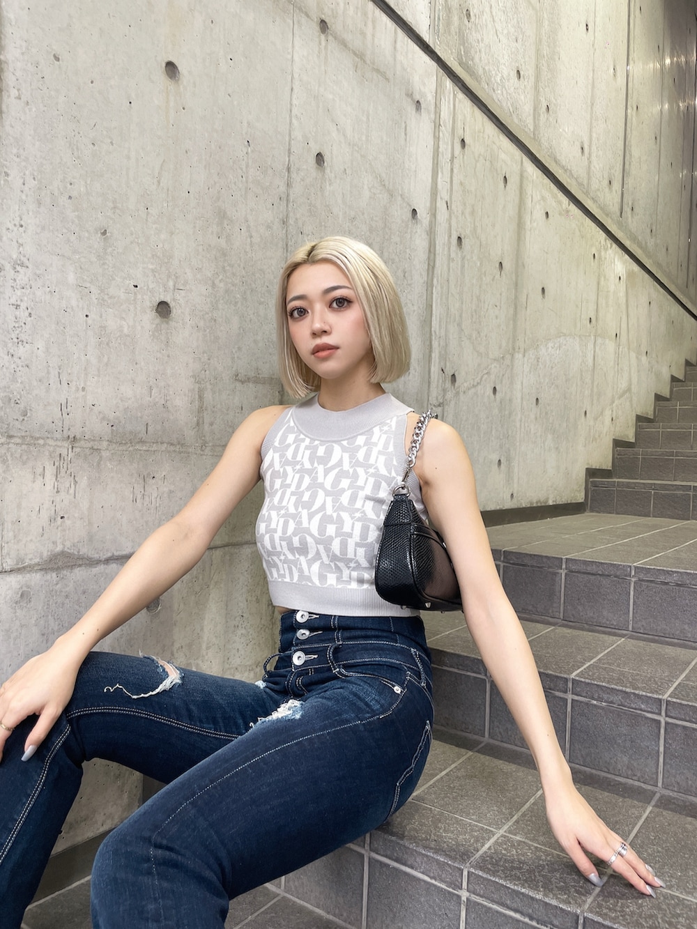 グレー系のニット/セーター、ブルー系のデニムパンツ、ブラック系のハンドバッグを着用したレディースの夏コーディネートの4枚目の写真