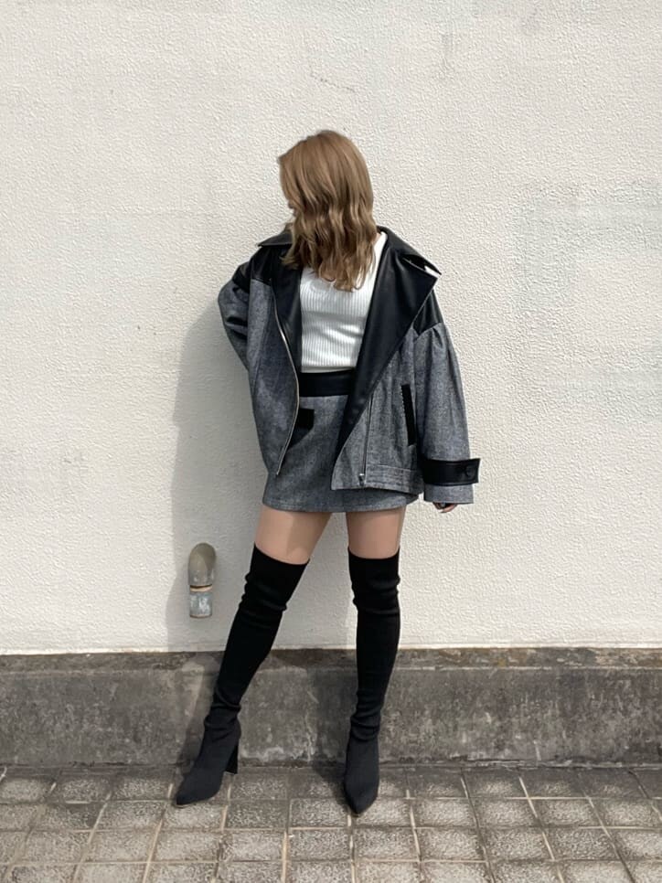 ブラック系のライダースジャケット、ホワイト系のニット/セーター、ブラック系のスカートを着用したレディースの秋コーディネートの2枚目の写真