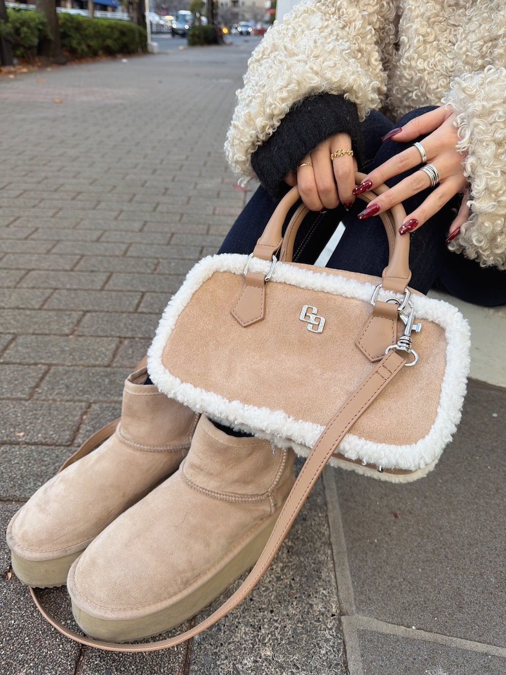 ホワイト系のブルゾン、ブルー系のデニムパンツ、ベージュ系のショルダーバッグを着用したレディースの冬コーディネートの4枚目の写真