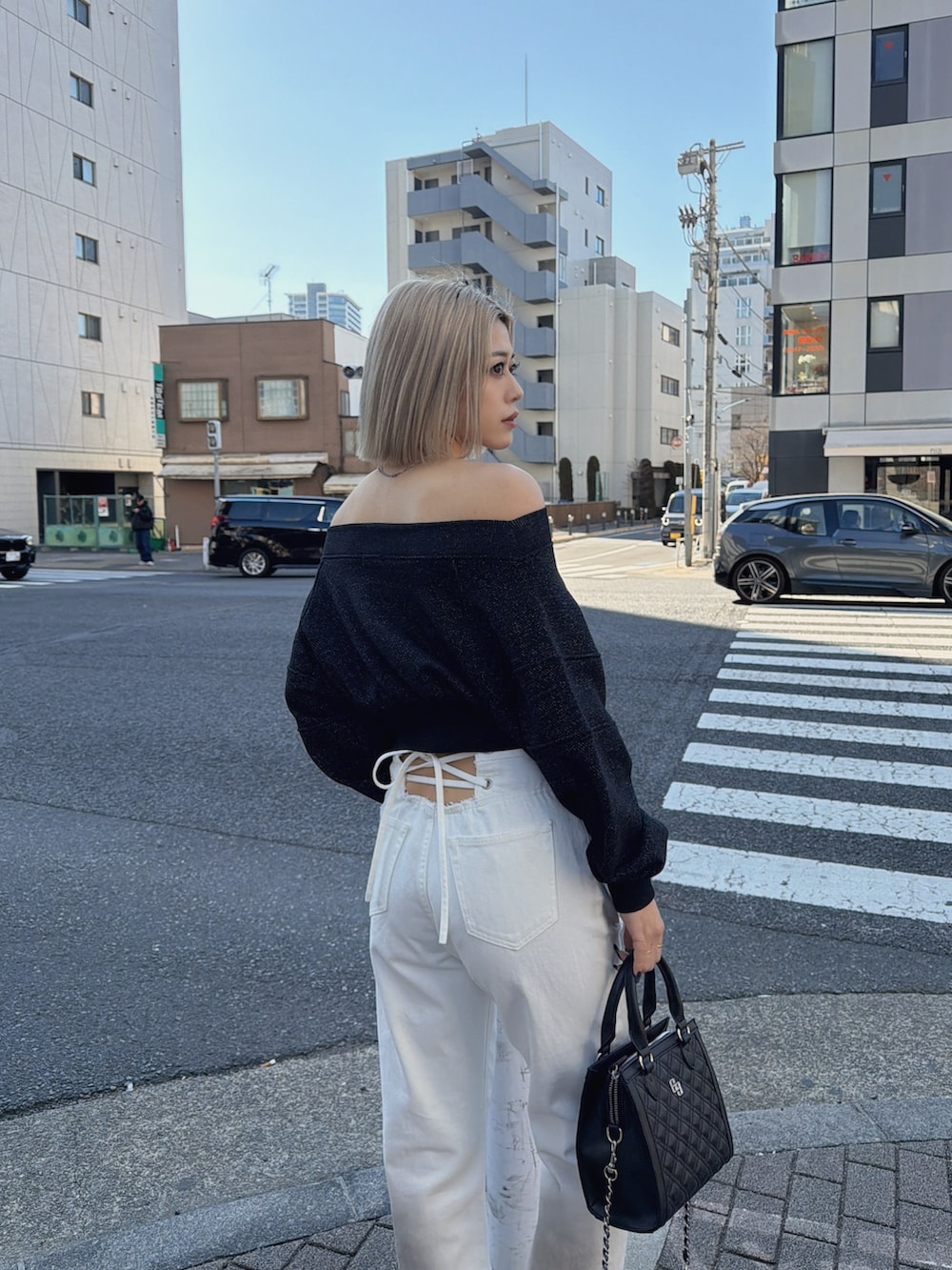 ブラック系のTシャツ/カットソー、ホワイト系のデニムパンツ、ブラック系のショルダーバッグを着用したレディースの冬コーディネートの5枚目の写真