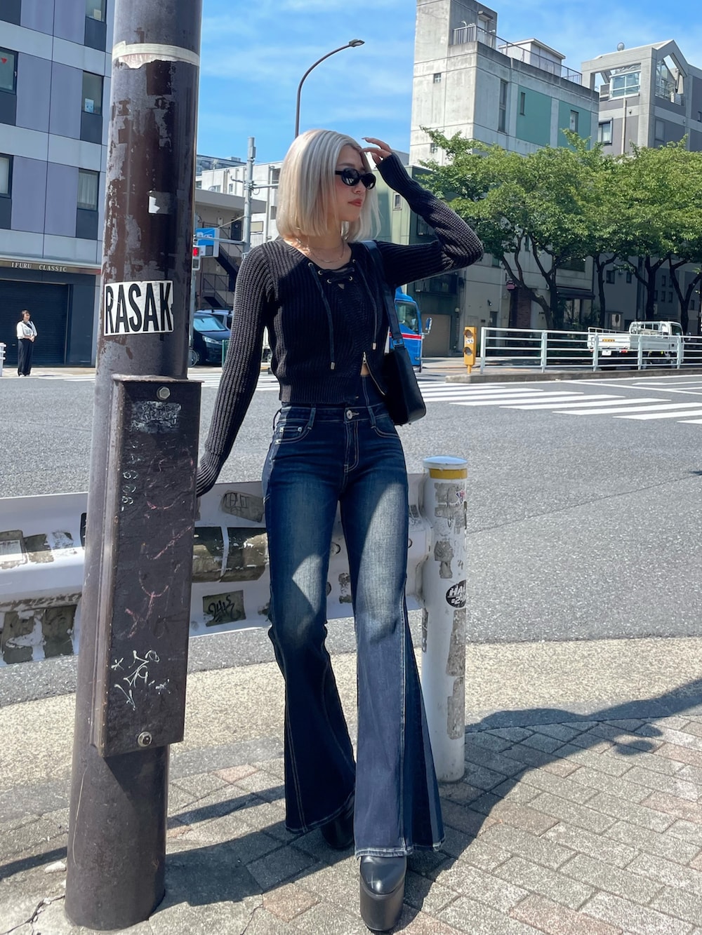 ブラック系のニット/セーター、ブルー系のデニムパンツ、ブラック系のブーツを着用したレディースの秋コーディネートの2枚目の写真