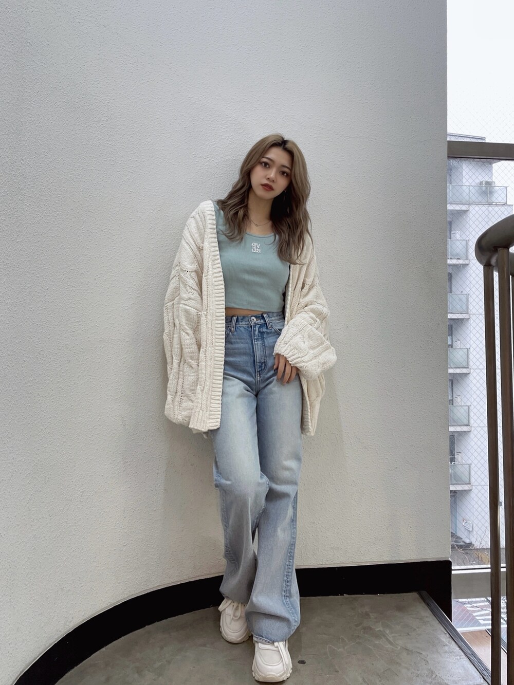 ホワイト系のカーディガン/ボレロ、グリーン系のTシャツ/カットソー、ブルー系のデニムパンツを着用したレディースの冬コーディネートの2枚目の写真