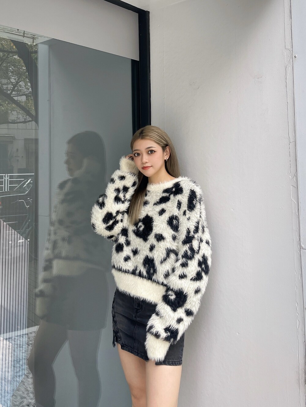 ホワイト系のニット/セーター、ブラック系のデニムスカート、ブラック系のブーツを着用したレディースの冬コーディネートの3枚目の写真