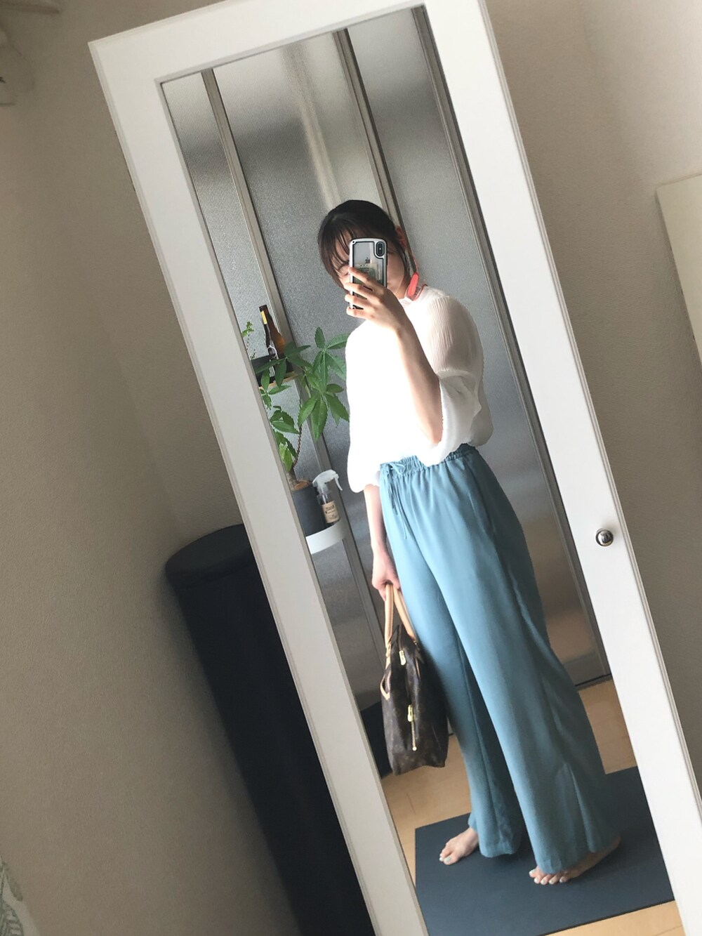 ブルー系のスラックス、ホワイト系のTシャツ/カットソー、ブラウン系のトートバッグを着用したレディースの夏コーディネートの3枚目の写真