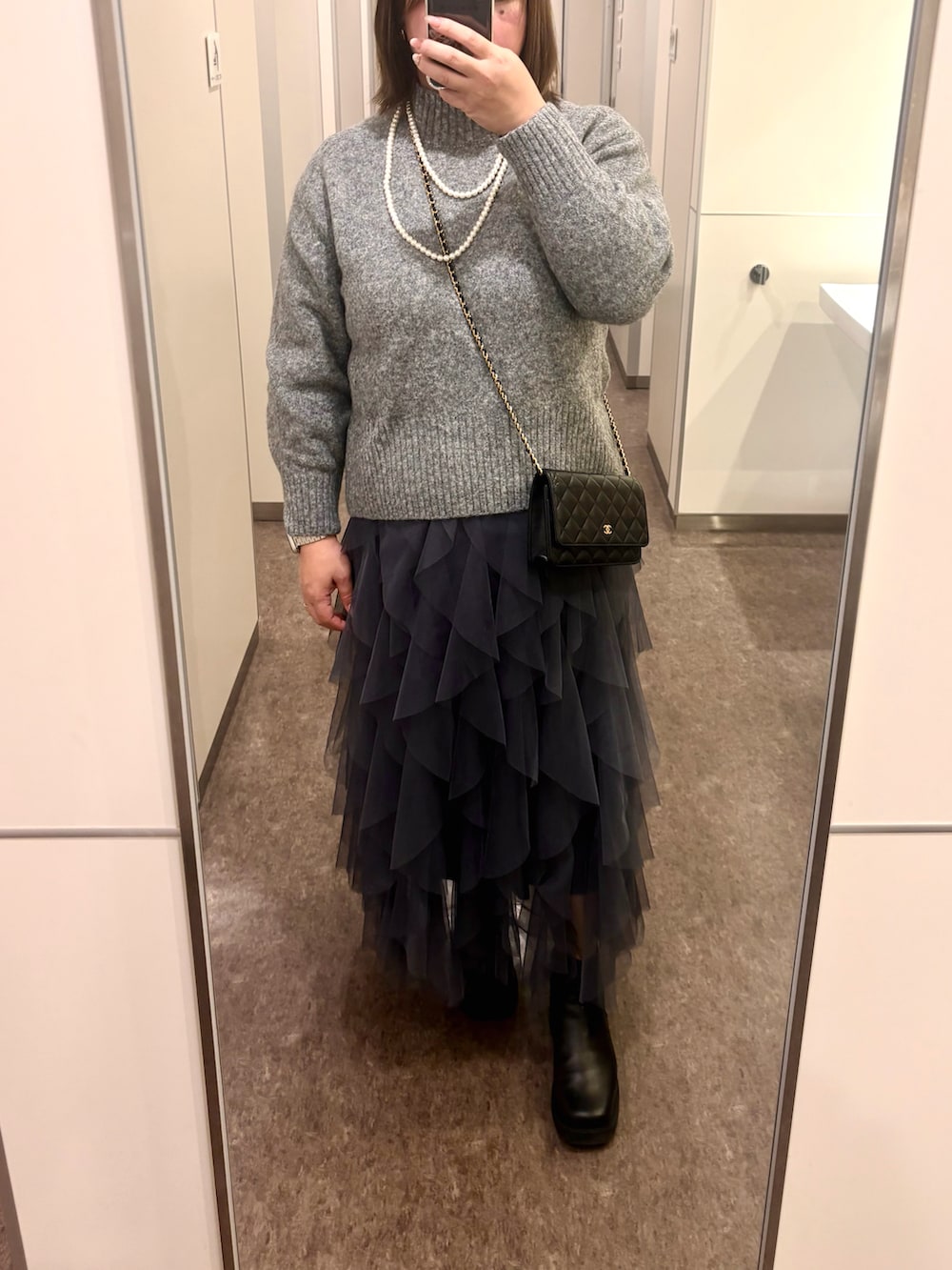 ブラック系のブルゾン、グレー系のニット/セーター、グレー系のスカートを着用したレディースの冬コーディネートの2枚目の写真
