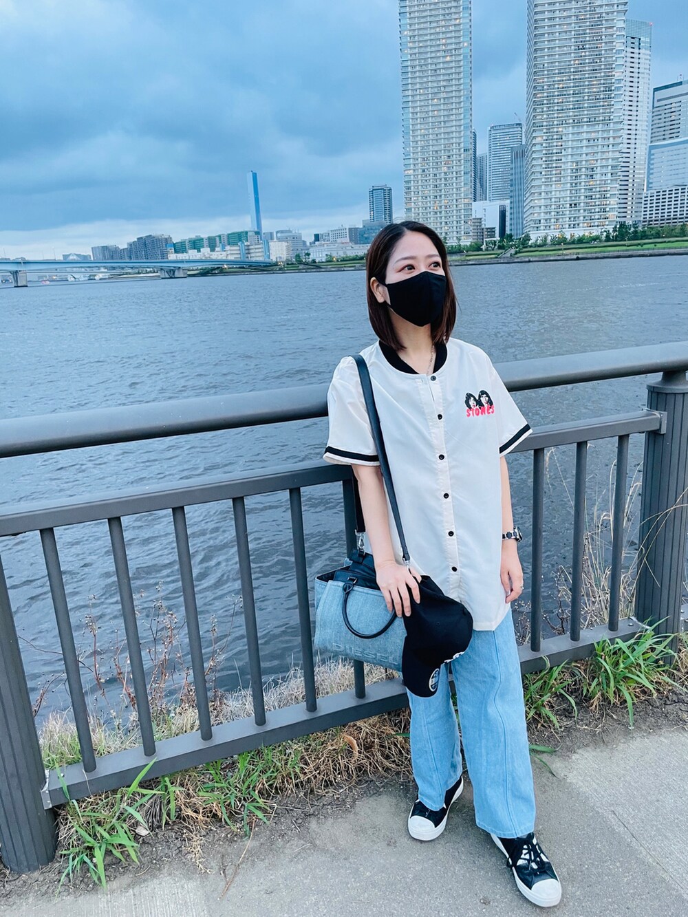 ブルー系のデニムパンツ、ホワイト系のシャツ/ブラウス、ブルー系のハンドバッグを着用したレディースの夏コーディネートの2枚目の写真