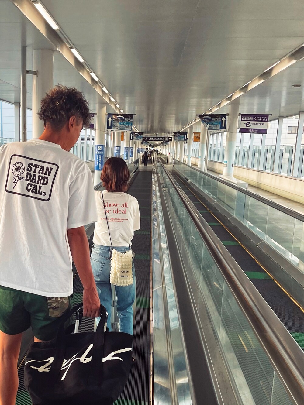 ホワイト系のTシャツ/カットソー、グリーン系のパンツ、ブラック系のサンダルを着用したメンズの夏コーディネートの2枚目の写真