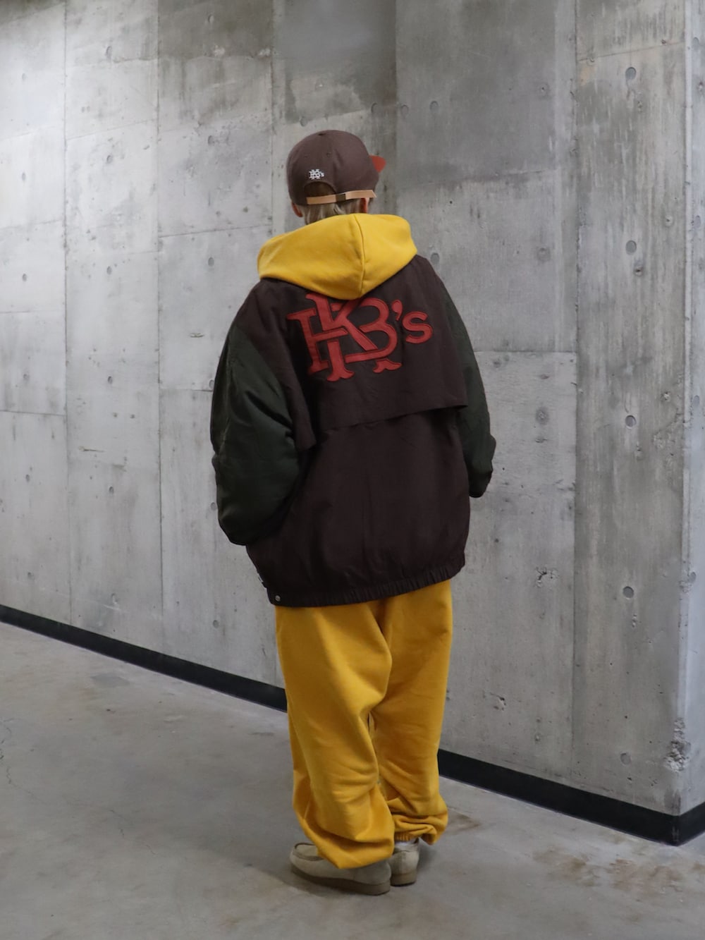 イエロー系のパーカー、イエロー系のスウェットパンツ、ブラウン系のナイロンジャケットを着用したレディースの春コーディネートの3枚目の写真