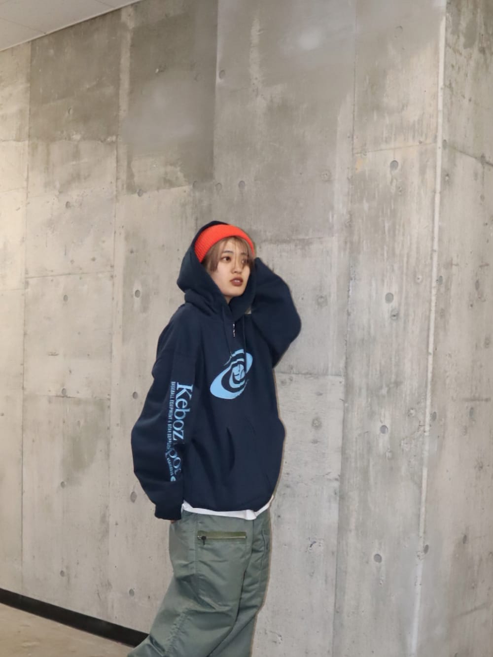 ブルー系のパーカー、グリーン系のカーゴパンツ、オレンジ系のニットキャップ/ビーニーを着用したレディースの春コーディネートの3枚目の写真