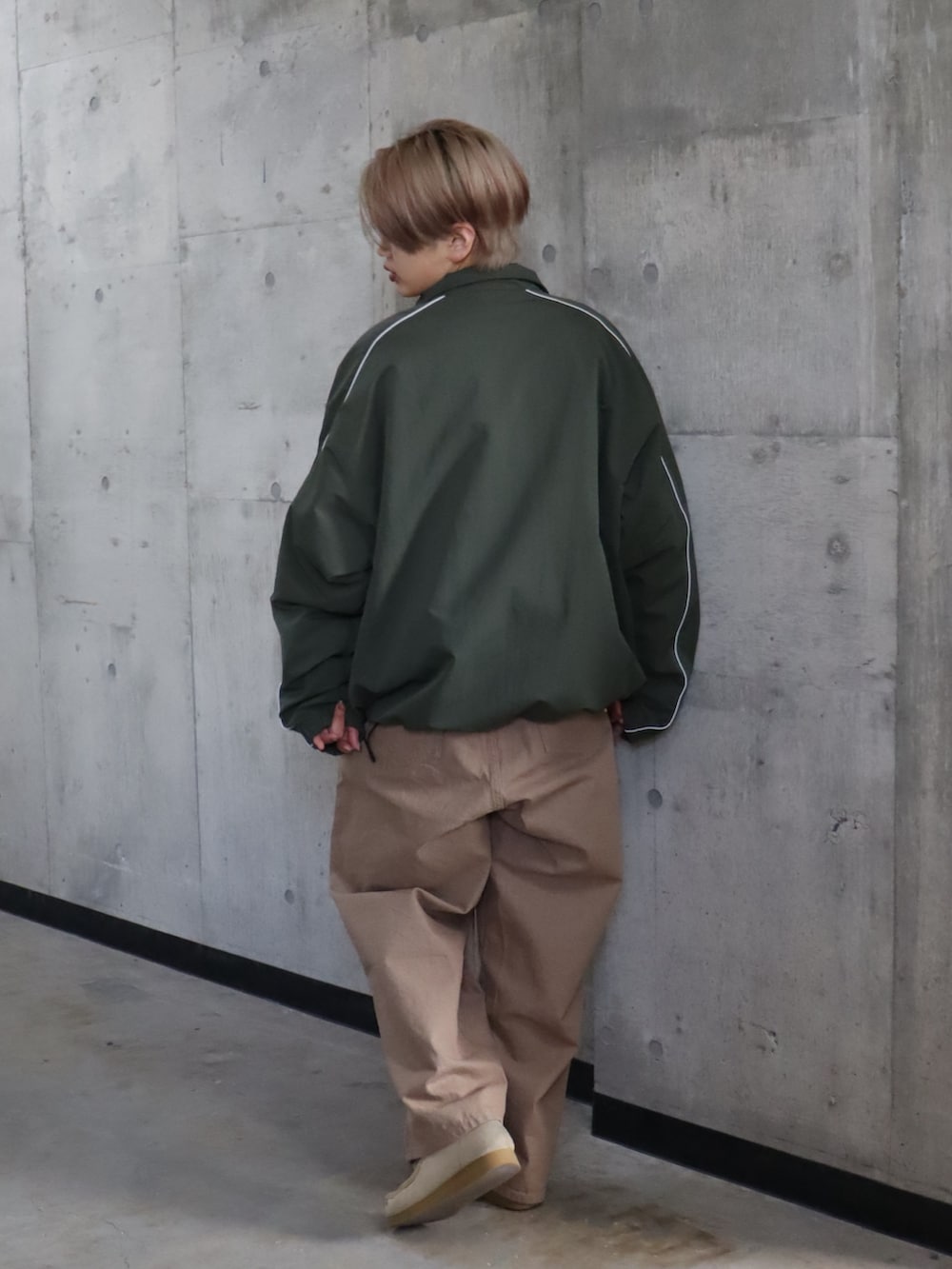 グリーン系のナイロンジャケット、ベージュ系のデニムパンツを着用したレディースの春コーディネートの5枚目の写真