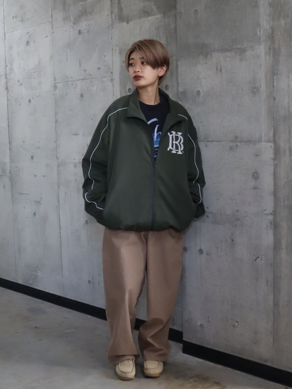 グリーン系のナイロンジャケット、ベージュ系のデニムパンツを着用したレディースの春コーディネートの2枚目の写真