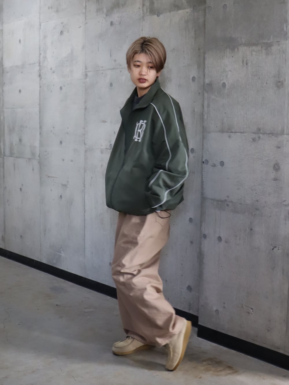 グリーン系のナイロンジャケット、ベージュ系のデニムパンツを着用したレディースの春コーディネートの3枚目の写真