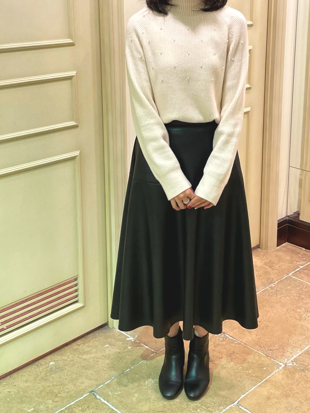 ホワイト系のニット/セーター、ブラック系のスカート、ブラック系のブーツを着用したレディースの秋コーディネートの2枚目の写真