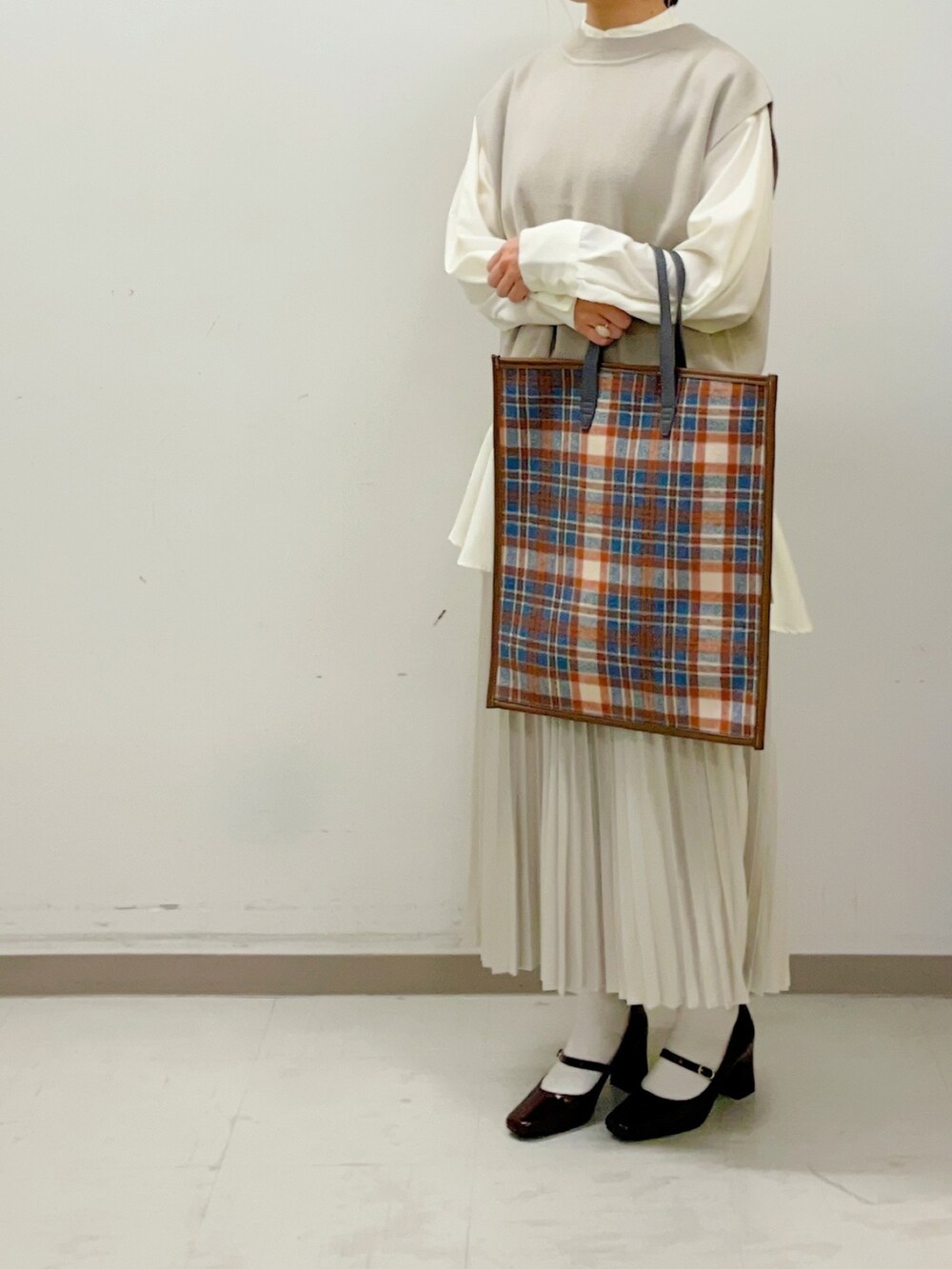 レッド系のパンプス、ホワイト系のスカート、ベージュ系のベストを着用したレディースの夏コーディネートの3枚目の写真